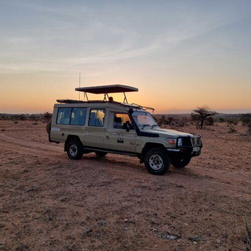 Safari 4x4 vehicle silhouetted against an African sunset